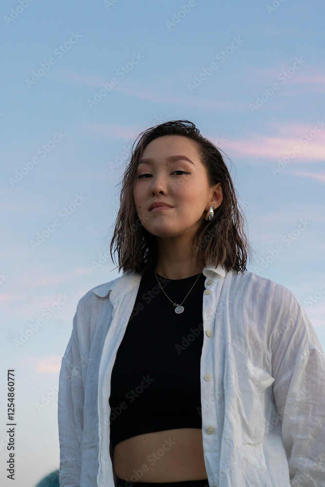 Portrait of a young Asian woman against the sky at sunset. Portrait of a young Asian woman against the sky at sunset.