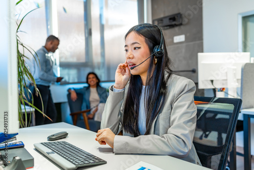 Asian operator working with headset in coworking office