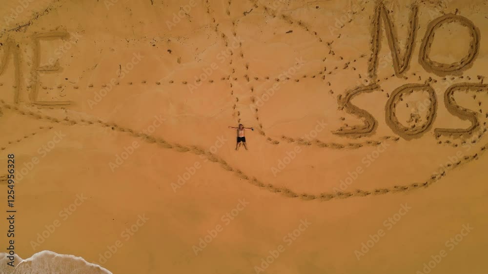 Aerial view of a man lying on a desert beach with inscriptions in the sand saying Leave me Here and No Sos, in São Tomé,Africa - Rising drone shot