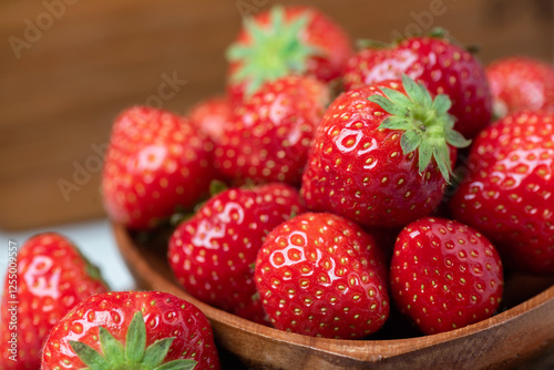Fresh juicy strawberries in wooden bowl closeup view, healthy summer time berry fruits