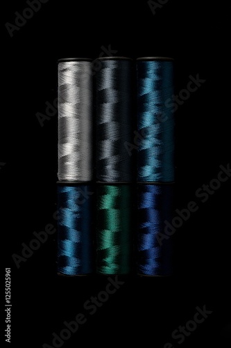 Six sewing thread spools arranged in two rows against deep black background, featuring silver, navy, and emerald threads with dramatic side lighting highlighting their silky texture. Generative AI photo