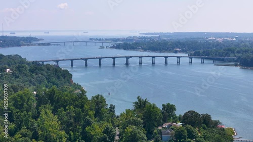 Wallpaper Mural A cinematic drone flies towards two bridges, one after the other, on a bright day with visible humidity in the air. Cargo ships float in the distance, while tree-lined edges guide the water below. Torontodigital.ca