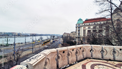 Street and tramway lines of Pest with the Liberty Bridge at the left end seen from the Rock Chapel on Gellert Hill at a winter sunset. Buda on the left rear side of the Danube bank, Budapest, Hungary.