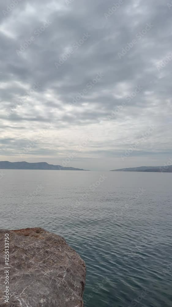 Experience the serene beauty of Lika-Senj with a breathtaking view of a cloudy sky, calm waters, distant mountains, and rocky shoreline. Perfect for nature lovers and explorers. Experience the serene beauty of Lika-Senj with a breathtaking view of a cloudy sky, calm waters, distant mountains, and rocky shoreline. Perfect for nature lovers and explorers.