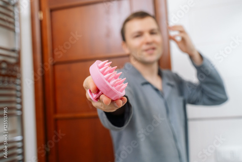 Young man with hair scalp massager photo