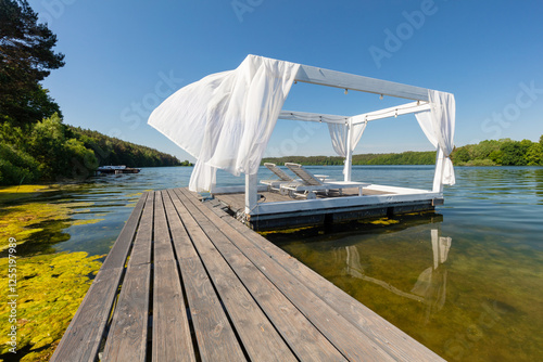Relaxing cabana on wooden dock over calm lake. Kashubia region in Poland.