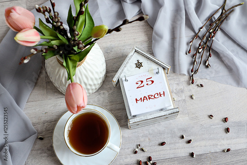 Calendar for March 25: numbers 25, name of the month March in English on a decorative calendar, cup, bouquet of tulips photo