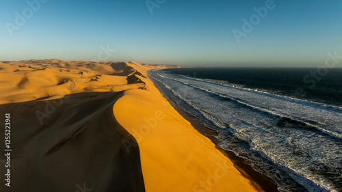 Aerial drone view of the ocean shore beaches next to the Namib dunes on a beautiful day of adventure at sunset, Namibia, Africa