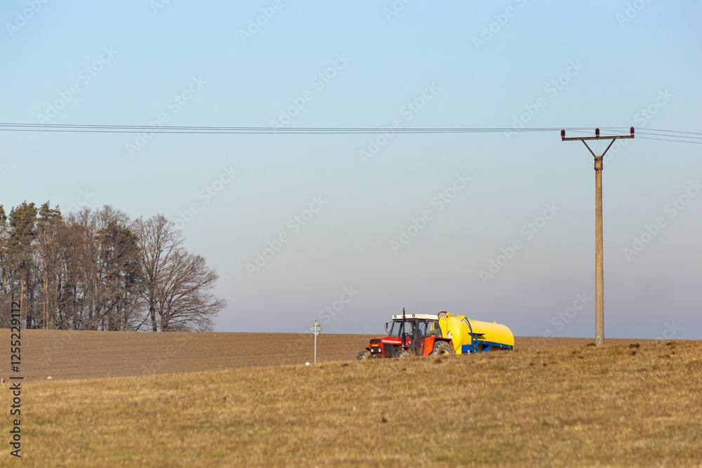 A tractor drives along a road in the countryside on a cold winter morning.