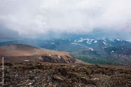 Dramatic top view from stony pass to vivid green alpine valley in sunlight ag...