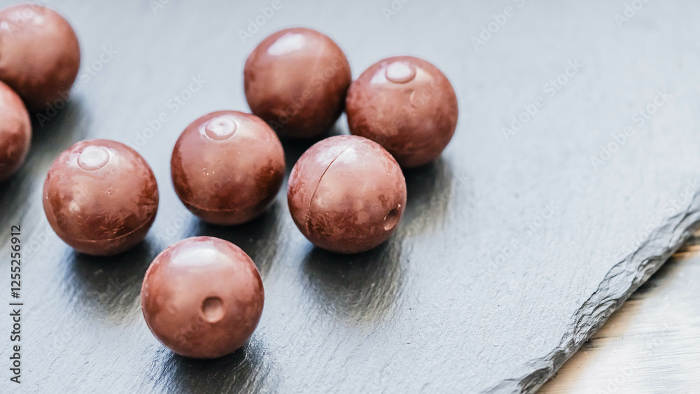 Obraz premium Schokoladenpralinen in sanftem Licht auf dunklem Schiefer
