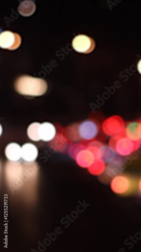 Vertical night video. Cars flow out of focus on road. Red and white lights bokeh. Concept of traffic jam on roadway, road, speed, travel, driving, trip. Blurred background. City street. Copy space