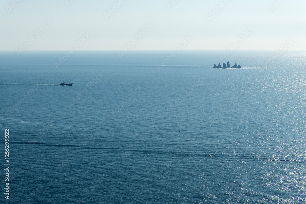 rock and boats on the sunlight-reflected sea rock and boats on the sunlight-reflected sea