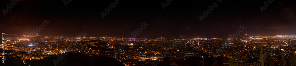 Obraz premium A stunning panoramic night view of Barcelona from Tibidabo, Catalonia, Spain, showcasing the illuminated cityscape, iconic landmarks, and a vibrant urban glow stretching into the horizon.
