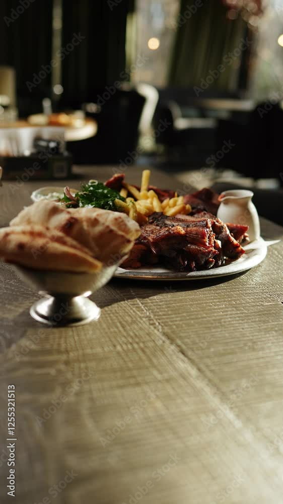 Delicious barbecue platter served with crispy fries and fresh greens at a cozy restaurant in the evening Delicious barbecue platter served with crispy fries and fresh greens at a cozy restaurant in the evening