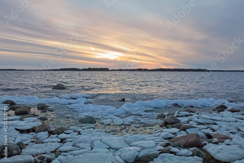 View of sunset from snow and ice covered rocky seashore on a cold winter day, Lauttasaari, Helsinki, Finland. photo