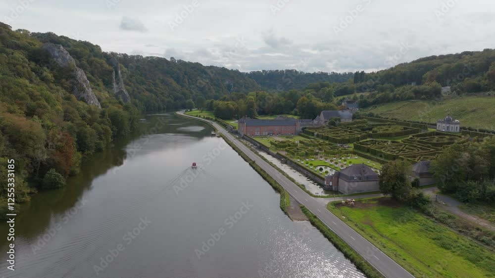 Drone shot following a small boat along a river in a valley surrounded by trees, gardens and lush landscape on a sunny day Drone shot following a small boat along a river in a valley surrounded by trees, gardens and lush landscape on a sunny day