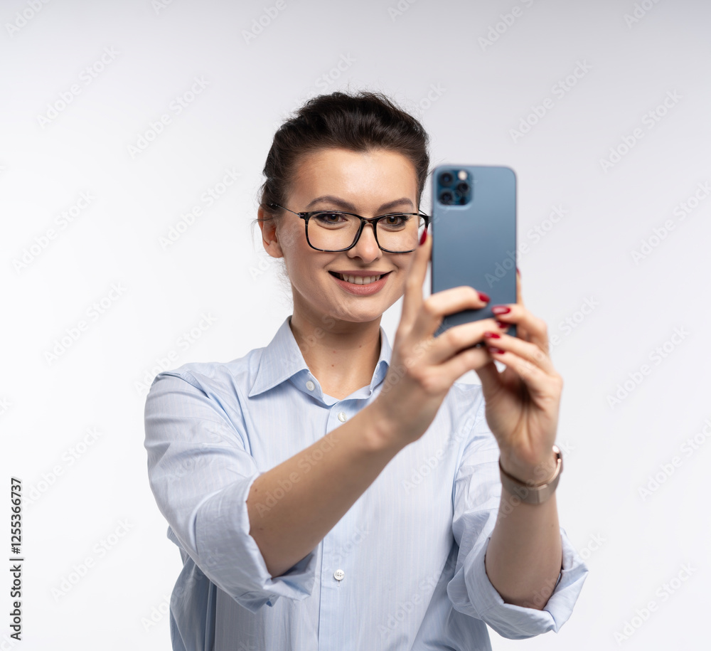 Smiling business woman in eyeglasses holding smartphone and using over white Smiling business woman in eyeglasses holding smartphone and using over white