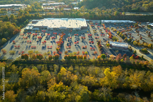 Aerial view grocery shopping mall and many colorful cars parked on parking lot with lines and markings for parking places and directions. Place for vehicles in front of a strip mall plaza