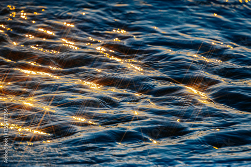 Obraz na plátně Sunlight reflects on the rippling water, creating a golden, shimmering effect