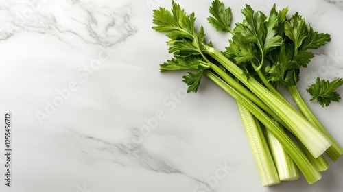 A visually appealing arrangement of vibrant green celery stalks on a clean marble surface, showcasing freshness and simplicity in a culinary context. photo