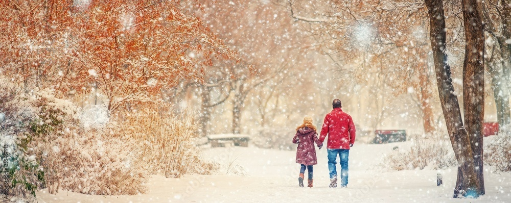 Father and daughter walking in snowy winter park with colorful trees and falling snowflakes Father and daughter walking in snowy winter park with colorful trees and falling snowflakes