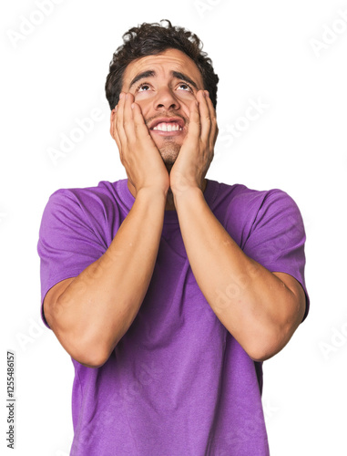 Young Hispanic man in studio whining and crying disconsolately. photo