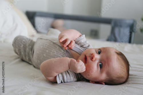 Cute baby girl lying on bed in bedroom at home photo