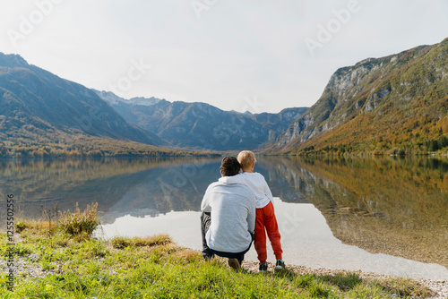 Father and son looking at mountains near lake photo