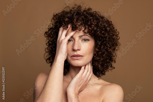 Woman with hands in hair against brown background photo