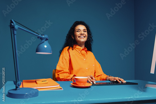 Happy worker with curly hair sitting at colorful desk photo