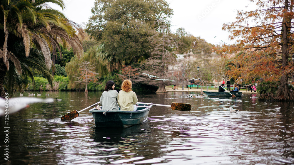 Lesbian couple rowing boat near trees in lake at Ciutadella Park, Barcelona, Spain Lesbian couple rowing boat near trees in lake at Ciutadella Park, Barcelona, Spain