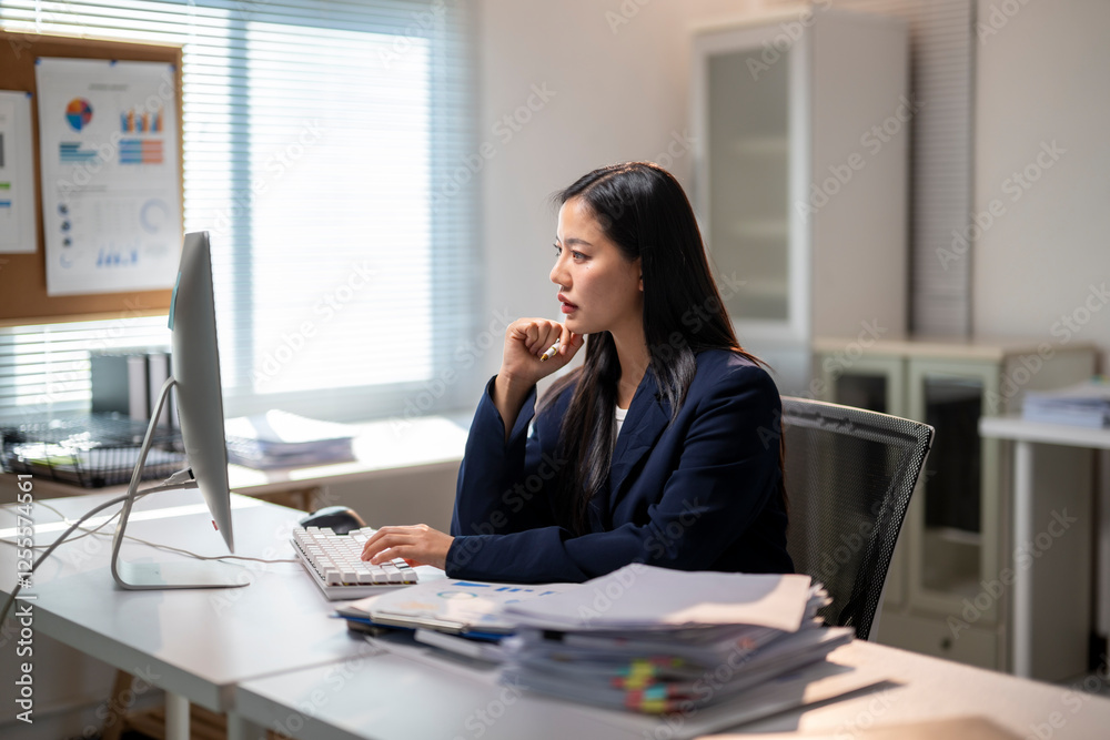A woman is sitting at a desk with a computer monitor A woman is sitting at a desk with a computer monitor