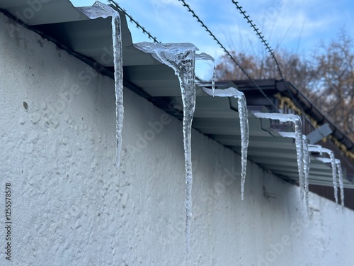 Long icicles on a concrete fence with barbed wire