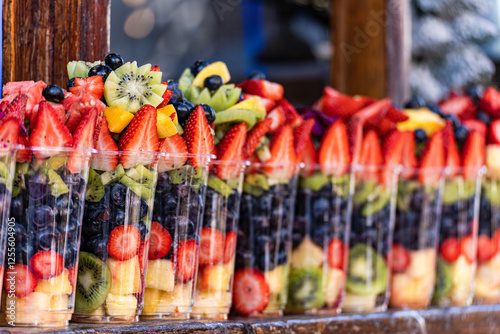 Close-up of rows of plastic cups filled with assorted fresh fruit on a shelf photo