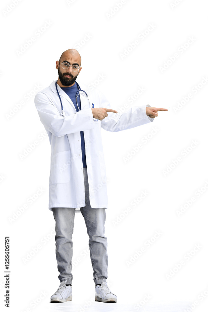 The male doctor, on a white background, in full height, points to the side