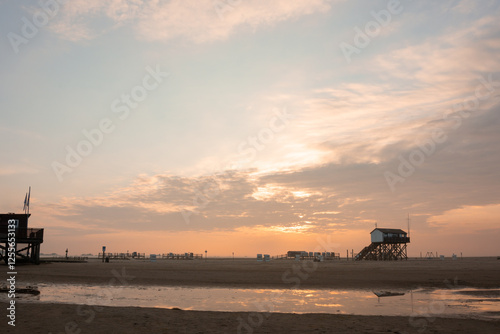 Obraz na płótnie Breiter Sandstrand mit Pfahlbau in St. Peter-Ording an der Nordsee bei Sonnenaufgang. w salonie