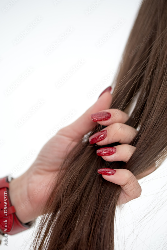 Fototapeta premium Human hand holding brown hair against white background, close up