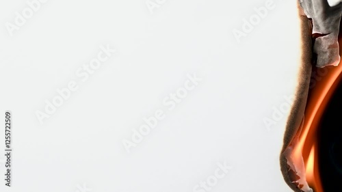 Closeup view of burning paper with fire. Fire consumes white paper with a black background