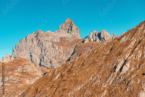 Impressive Bobotov Kuk peak and rock formation dominates the Durmitor landscape under a vibrant blue sky, showcasing the raw beauty of nature photo