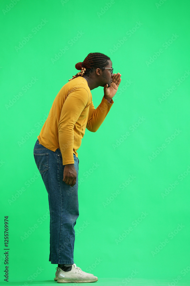 A man in a yellow sweater on a green background tell some secret, in profile A man in a yellow sweater on a green background tell some secret, in profile