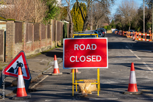 Big sign white letters on red plate saying road closed coned, quiet urban area, sunny day photo