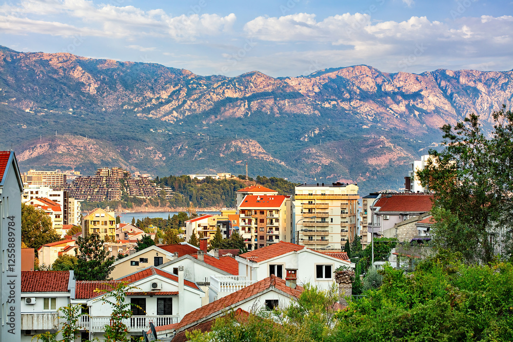 Houses of Budva nestled among the hills with a breathtaking mountain backdrop in sunny Montenegro.