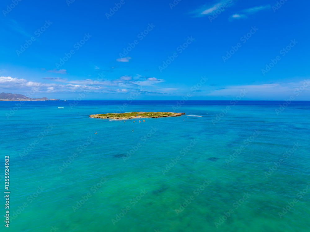 Lush green island surrounded by turquoise waters, with small boats and paddleboarders nearby, captured in an aerial view near Oahu, Hawaii. Lush green island surrounded by turquoise waters, with small boats and paddleboarders nearby, captured in an aerial view near Oahu, Hawaii.
