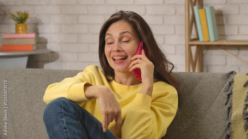 Young woman spending day at home sitting on the sofa in the living room, talking answering call on smartphone, flirting smiling expression. Young woman spending day at home sitting on the sofa in the living room, talking answering call on smartphone, flirting smiling expression.