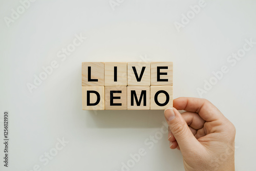 Hand holding wooden blocks spelling LIVE DEMO against a white background