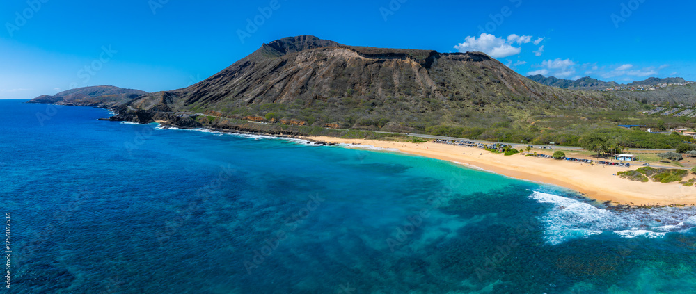Obraz premium Aerial view of Oahu Island's beach with turquoise waters, golden sand, and Diamond Head crater in the background under clear blue skies.