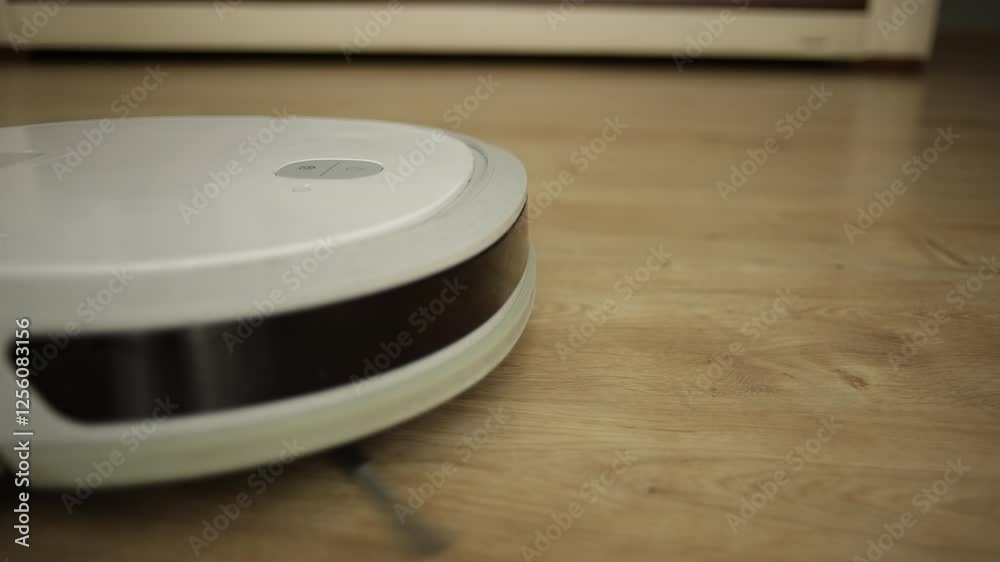 close-up view of a hand pressing the start button on a robotic vacuum ...