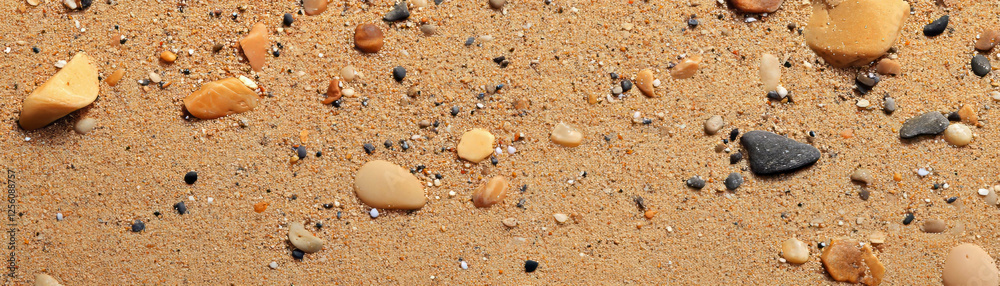 Scattered pebbles on sandy shore at water's edge creating a vibrant coastal view Scattered pebbles on sandy shore at water's edge creating a vibrant coastal view