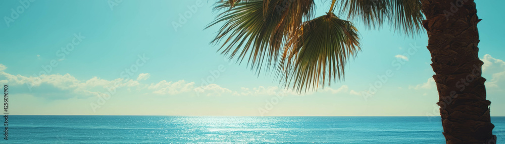 Naklejka premium View of ocean horizon framed by palm tree under clear blue sky